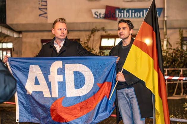 AfD Demonstranten protestieren gegen Dragqueen-Lesung für Kinder vor der Stadtbibliothek Moosach, München, 1. Dezember 2025 Deutschland, München, 1. Dezember 2025, AfD Demonstranten mit Deutschlandfahne protestieren gegen Dragqueen-Lesung für Kinder vor der Stadtbibliothek Moosach, Dragqueen Vicky Voyage macht währenddessen eine Lesung in der Stadtbibliothek Moosach, sie liest vor Familien mit Kindern aus Kinderbüchern vor, vor der Bibliothek in der Hanauer Straße kommt es während der Lesung zu heftigen Protesten von Rechtsextremen, auch eine christlich-fiundamentalistische Gruppe hatte gegen die von ihnen so genannte Frühsexualisierung von Kindern protestiert, Montagnachmittag ab 16 Uhr im Stadtteil Moosach, Bayern