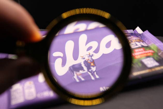 Drei Schokoladentafeln der Marke Milka liegen auf einer Schieferplatte. Eine Lupe zeigt auf das Markenzeichen der Schokoladensorte, die hellviolett bemalte Kuh. Schnelsen Hamburg *** Three Milka brand chocolate bars lie on a slate A magnifying glass points to the trademark of the chocolate variety, the light purple painted cow Schnelsen Hamburg