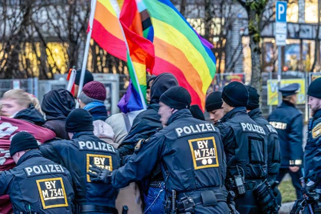 Antifa-Demonstranten werden von der Polizei abgedrängt, am Rande der Dragqueen-Lesung von Vicky Voyage, Lesung für Kinder in der Stadtbibliothek Moosach, München, 1. Dezember 2025 Deutschland, München, 1. Dezember 2025, linke Proteste gegen Rechtsextreme, die gegen eine Dragqueen-Lesung in der Stadtbibliotherk Moosach demonstrieren, Polizisten drängen eine Gruppe von Antifa-Demonstranten mit Regenbogenflaggen ab, die sich nicht hinter eine vorgesehene Absperrung begeben wollte, Gruppe darf auf der anderen Straßenseite der Hanauer Straße weiter demonstrieren, Dragqueen Vicky Voyage liest vor Familien mit Kindern aus Kinderbüchern vor, vor der Bibliothek in der Hanauer Straße war es während der Lesung zu heftigen Protesten von Recht
