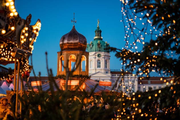 Weihnachtslichter und Tannenzweige rahmen die Marktarchitektur und das Schloss Charlottenburg ein. Abendliche Adventsstimmung auf einem der beliebtesten Berliner Weihnachtsmärkte. Stimmungsvolle Lichter am Weihnachtsmarkt Charlottenburg Schlosskulisse bei Abendlicht *** Christmas lights and fir branches frame the market architecture and Charlottenburg Palace Evening Advent atmosphere at one of Berlins most popular Christmas markets Atmospheric lights at Charlottenburg Christmas market Palace backdrop in the evening light