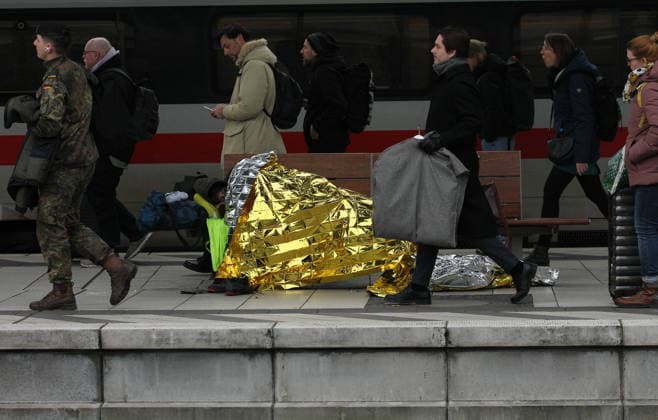 Ein Obdachloser liegt auf einer Sitzbank auf dem Bahnsteig im Hauptbahnhof Hamburg. Reisende gehen an ihm vorbei. St. Georg Hamburg *** A homeless man lies on a bench on the platform at Hamburg Central Station Travelers walk past him St Georg Hamburg