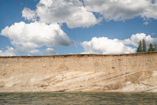 Creative Highlights World Striated layers of a river bank under blue skies and clouds Whitefish, Montana, United States CR_AXTH251205-1863368-01