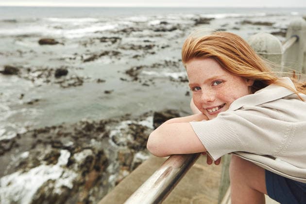 Beach, happy and portrait of child on promenade for summer vacation, getaway or weekend trip. Outdoor, relax and girl kid with smile on boardwalk by ocean for seaside view on holiday for travel model released property released Copyright: xx
