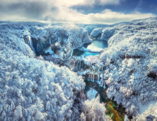 Aerial drone view of frozen waterfalls and turquoise lakes in snowy forest at sunrise. Plitvice Lakes National Park, Croatia. Winter landscape with icy cascades, trees in snow. Scenic nature. Top view Model Released DenisBilytskyi_ID32329_1102316_007 Copyright: xx