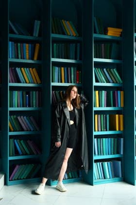 Woman stands in front of colorful bookshelves in a bright room Saint Petersburg, Saint Petersburg, Russia R_KNCD251208-1905789-01 ,model released, Symbolfoto