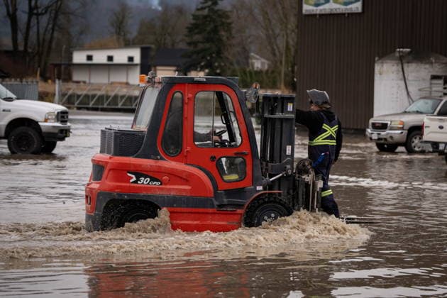 December 11, 2025, Vancouver, Bc, CANADA: A man rides on a fork lift to save equipment at Enviro-Corp Recycling which flooded near the Sumas border crossing in Abbotsford B.C., on Thursday, December 11, 2025. Vancouver CANADA  - ZUMAc35_ 20251211_zaf_c35_059 Copyright: xEthanxCairnsx