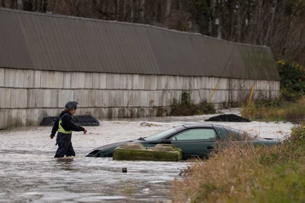 December 11, 2025, Vancouver, Bc, CANADA: A man smokes a cigarette while walking to a submerged vehicle during flooding in Abbotsford B.C., on Thursday, December 11, 2025. Vancouver CANADA  - ZUMAc35_ 20251211_zaf_c35_060 Copyright: xEthanxCairnsx