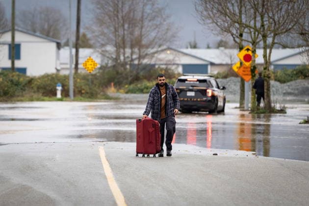 December 11, 2025, Vancouver, Bc, CANADA: A man carries a suitcase from flooded areas in Abbotsford B.C., on Thursday, December 11, 2025. Vancouver CANADA  - ZUMAc35_ 20251211_zaf_c35_110 Copyright: xEthanxCairnsx