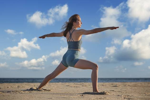 Eine Frau praktiziert bei Sonnenuntergang die Pose Warrior 2 Virabhadrasana 2 am Strand und verkörpert Kraft und Frieden in ihrer Yogapraxis A woman practices Warrior 2 Virabhadrasana 2 pose on the beach during sunset, embodying strength and peace in her yoga practice Copyright: imageBROKER DmitryxRukhlenko ibxdmr15865963.jpg ,model released, Symbolfoto ,property released