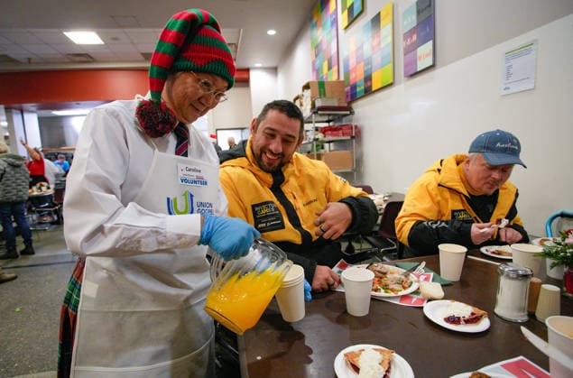 (251213) -- VANCOUVER, Dec. 13, 2025 -- A volunteer serves drinks during the annual Christmas meal event in Vancouver, British Columbia, Canada, on Dec. 12, 2025. (Photo by Xinhua) CANADA-VANCOUVER-CHRISTMAS MEALS LiangxSen 