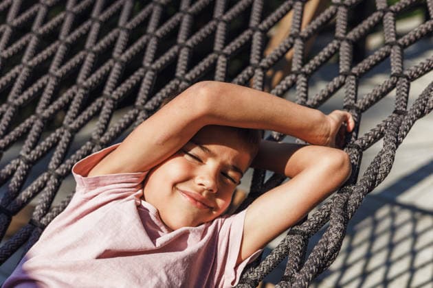 Boy relaxing in hammock under the sun A young boy relaxes comfortably in a hammock, enjoying the warmth of the sunlight. His smile and closed eyes convey a sense of peace and contentment in a serene outdoor setting. Model Released AlinaKandybka_ID31636_1075834_006 Copyright: xAlinaxKandybkax RECORD DATE NOT STATED