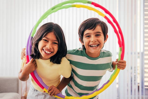MR_ID31765_22979_AlexPelaez.jpg, MR_ID31765_22980_SarahRamirez.jpg Two cheerful children enjoying indoor play with a vibrant hula hoop, sharing smiles and laughter in a bright room, highlighting the joy of friendship and carefree childhood Model Released AscProductions_ID31765_1080009_032 Copyright: xAscxProductionsx RECORD DATE NOT STATED