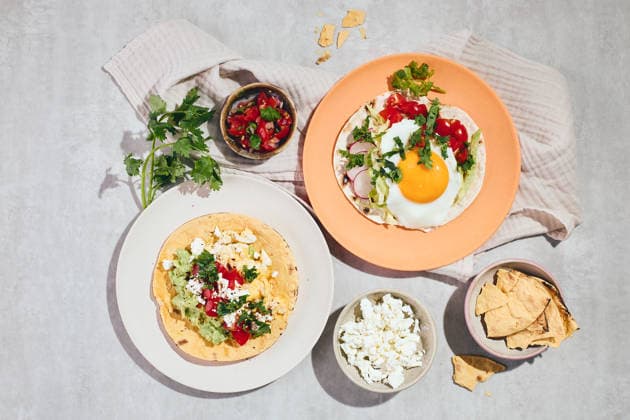 Top view of huevos rancheros breakfast with vibrant ingredients Top view of huevos rancheros on vibrant plates, featuring fried eggs on tortillas, garnished with fresh cilantro, tomatoes, and avocado, set on a rustic fabric-covered table. Model Released IrinaBurakova_ID31425_1068693_011 Copyright: xIrinaxBurakovax RECORD DATE NOT STATED