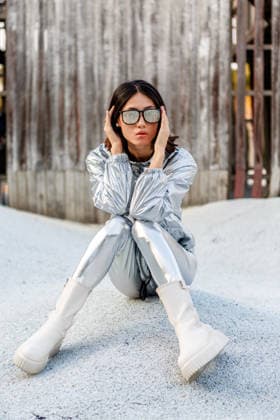 A stylish Asian woman poses confidently in a sleek silver suit, exuding modern elegance. Her sophisticated look is highlighted by trendy sunglasses and white boots. Model Released JuanAlgar_ID31575_1073651_018 Copyright: xJuanxAlgarx RECORD DATE NOT STATED