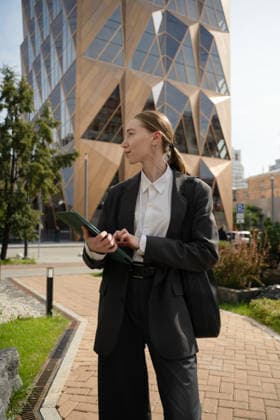 MR_ID31630_22889_AlenaZhdanova.jpg Business woman in an urban setting, confidently holding a tablet. She is standing outdoors in front of a modern glass building, exemplifying city life and professional ambition Model Released LiliyaSolopova_ID31630_1075603_011 Copyright: xLiliyaxSolopovax RECORD DATE NOT STATED