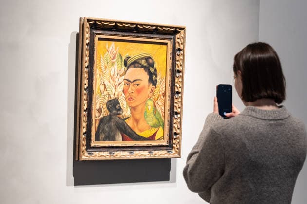 Sotheby s Icons and Bing Crosby Exhibitions press preview A visitor takes photo of Frida Kahlo Autorretrato con chango y loro sold for more than 3 million dollars on view during press preview at Sotheby s Icons and Bing Crosby Exhibitions in New York, NY on December 13, 2025. New York New York United States Copyright: LevxRadin