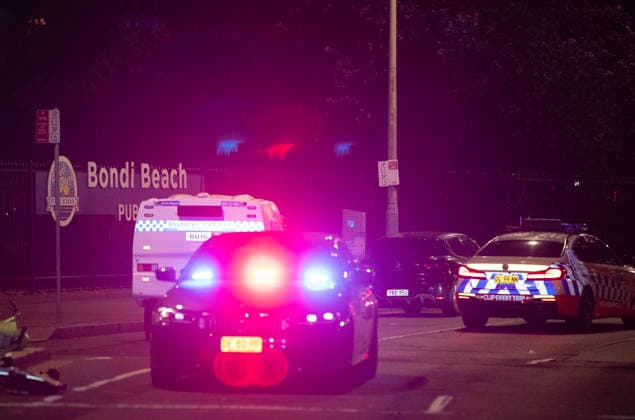 (251214) -- SYDNEY, Dec. 14, 2025 -- Police vehicles are seen near the shooting site at Bondi Beach in Sydney, Australia, on Dec. 14, 2025. At least 12 people have died after a shooting at Sydney s Bondi Beach on Sunday night, said New South Wales Premier Chris Minns. One of the offenders was among the dead and another one is in custody, the Australian Broadcasting Corporation (ABC) cited Minns as saying. ) (SpotNews) AUSTRALIA-SYDNEY-MASS SHOOTING MaxPing 