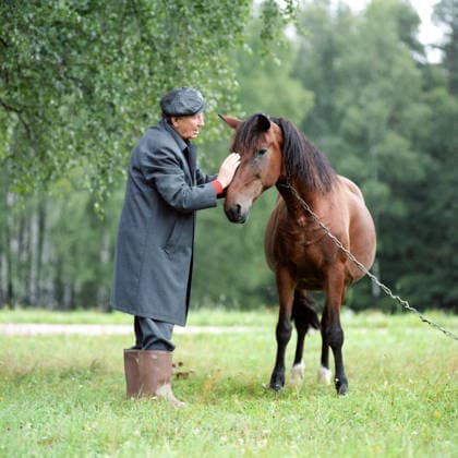 August 1-25, 1988. Pskov Region, USSR. Soviet poet and Hero of Socialist Labour Mikhail Dudin pets a horse at the Alexander Pushkin State Museum-Reserve in the village of Mikhailovskoye. The exact date of the photograph is unknown. Yuri Belinsky TASS  5362134