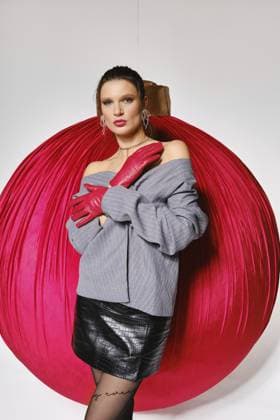 Ein Model steht in einem Studio mit einem großen roten Ornament hinter sich. Sie trägt ein graues Oberteil und einen schwarzen Rock. Ihre Hände sind mit roten Handschuhen bedeckt. Die Szene ist bereit für ein Modeshooting A model stands in a studio with a large red ornament behind her. She wears a grey top and a black skirt. Her hands are covered in red gloves. The scene is set for a fashion shoot Copyright: imageBROKER AlekseixIsachenko ibxaii15897266.jpg ,model released, Symbolfoto ,property released