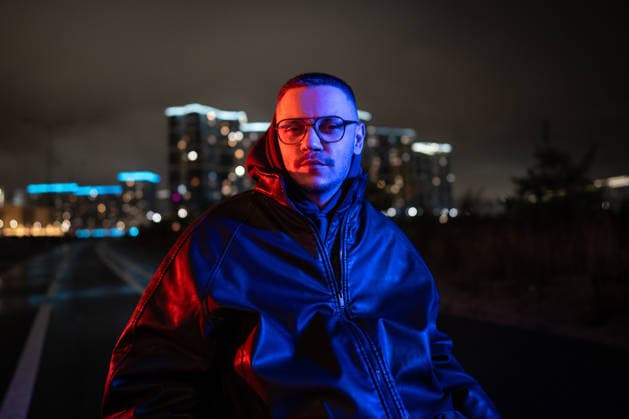 Porträt eines nachdenklichen behinderten Mannes im Rollstuhl in blauem, rotem Neon-RGB-Licht auf einem nächtlichen Spaziergang. Disabled young man in wheelchair looking at camera with focused expression, taking walk outdoors late at night in fresh air. Portrait of male with disability in blue red neon color rgb light. (License=RF) ,model released, Symbolfoto Copyright: xZoonar.com DmitriixMarchenkox 24318206 ,model released, Symbolfoto ,property released