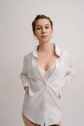 Selbstbewusste Frau im weißen Hemd, die ihre Schönheit in einem Haus zur Schau stellt A confident woman stands in a bright room wearing a loosely buttoned white shirt. The outfit reveals her elegance and beauty, highlighting her natural charm. Soft lighting accentuates the serene atmosphere, showcasing her poise. (License=RF) ,model released, Symbolfoto Copyright: xZoonar.com AndreyxGuryanovx 24323208 ,model released, Symbolfoto ,property released