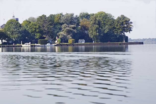 Ruhige Landschaft (Insel Wilhelmstein) am Seeufer mit dichter Baumreihe und Booten auf leicht gekräuseltem Wasser, Steinhude, Steinhuder Meer Tranquil landscape (Wilhelmstein Island) on the lakeshore with a dense row of trees and boats on slightly rippled water, Steinhude, Steinhuder Meer Copyright: imageBROKER BerndxDembkowski ibxbdd15932330.jpg