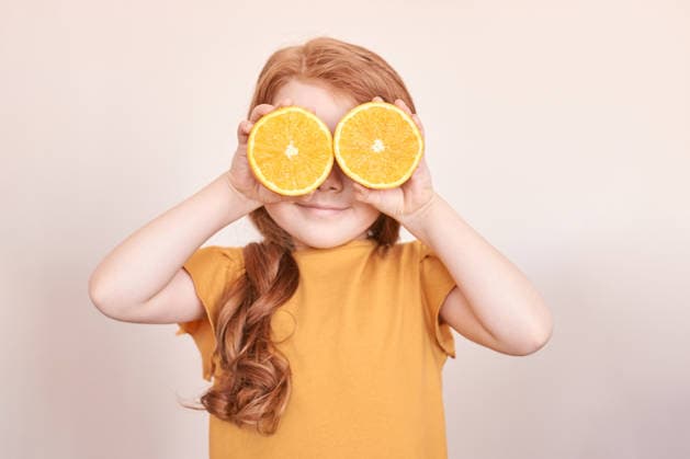Kaukasisches Kind mit roten Haaren, die die Augen mit orangefarbenen Scheiben bedecken, in verspielter Pose auf beigem Hintergrund Caucasian child with red hair covering eyes with orange slices in playful pose on beige background. (License=RF) ,model released, Symbolfoto Copyright: xZoonar.com ElenaxSafonovax 24340219 ,model released, Symbolfoto ,property released