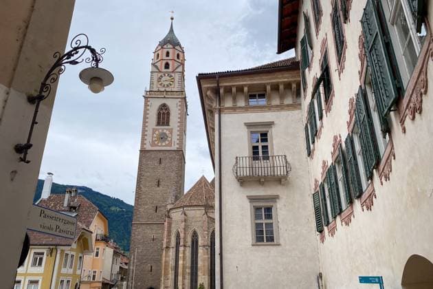 Kirche St. Nikolaus von Vicolo Passiria, Meran (Italien) View of St. Nicholas Church from Vicolo Passiria in Merano (Meran), Italy; gothic bell tower with clock and spire framed by old town facades under a sky with cloud (License=RF) Copyright: xZoonar.com FabianxMesebergx 24339929