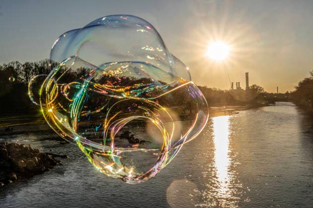 News Bilder des Tages Die tiefstehende Wintersonne taucht die Isar in ein magisches Licht, eine Seifenblase schillert im Licht, München, 18. Dezember 2025 Deutschland, München, 18. Dezember 2025, in schillernden Regenbogenfarben leuchtet eine Seifenblase in der Wintersonne, über der Isar wölbt sich ein strahlend blauer Himmel, ein sonniger Wintertag geht zu Ende, das Heizkraftwerk Süd am Horizont, ein Mann auf der Reichenbachbrücke lässt die Seifenblasen zur Freude der Passanten in den Himmel steigen, Donnerstagnachmittag, Temperaturen um die 10 Grad, Weihnachtszeit, Adventszeit, Winter, sonniges Winterwetter, Bayern, bayerisch,