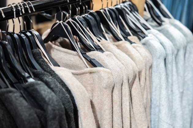 Eine Reihe von weichen Strickpullovern in neutralen Farbtönen (beige, grau, schwarz), die auf einer Stange in einem Bekleidungsgeschäft hängen. Row of soft knit sweaters in neutral shades (beige, gray, black) hanging on a rail in a clothing store. High quality photo (License=RF) Copyright: xZoonar.com KyryloxSyvunx 24332179
