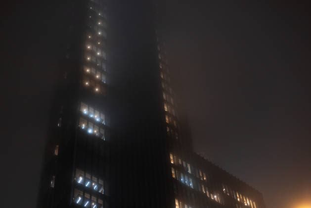Dramatische Ansicht städtischer Elektrizität und Lichtverschmutzung, während Bürofenster in einer nebligen Nacht intensiv leuchten. Neblige nächtliche Stadtlandschaft mit beleuchteten Bürogebäudefenstern, die durch dense. 1102833192