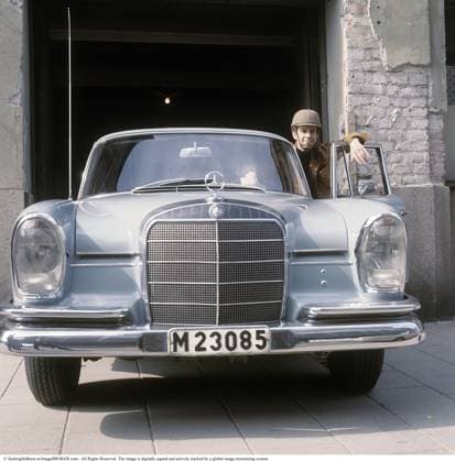 Der Autohelm wurde 1966 auf den Markt gebracht und war die Idee von Professor Bertil Aldman, der später Leiter der Abteilung für Verkehrssicherheit der Chalmers University of Technology wurde. Diese Sicherheitsinnovation wurde entwickelt, um Menschen vor schweren Kopfverletzungen zu schützen. Die Hersteller von Autohelmen sahen insbesondere vor der Umstellung auf Rechtsverkehr im Jahr 1967 eine Chance für höhere Verkaufszahlen. Der Helm war mit Stoff in modernen Farben und Mustern bezogen. Ein Tretorn Autohelm von Tretorn kostete rund 60 Kronen. Seltsamerweise passierten weniger Unfälle als vor dem Wechsel zum Rechtsverkehr. Im Bild: Schauspieler Jarl Kulle auf seinem Mercedes Benz 220 SE Modelljahr 1965, trägt einen Autohelm.1970 The c Copyright: imageBROKER Sjoberg ibljsj15943745.jpg
