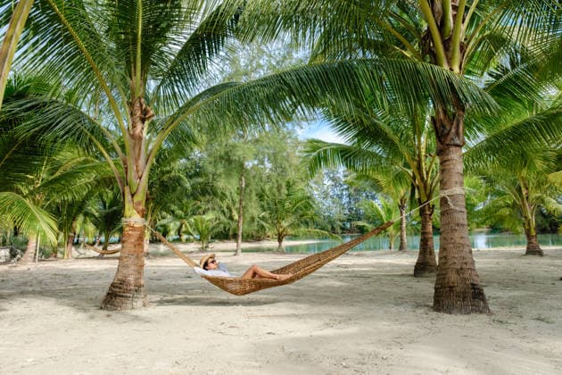 Entspannen in einer Hängematte umgeben von üppigen Palmen auf der Insel Koh Kood in Thailand A peaceful scene of an Asian woman lounging in a hammock beneath tall palm trees on Koh Kood Island. Soft sandy beach and tranquil water create a tropical paradise in Thailand. (License=RF) ,model released, Symbolfoto Copyright: xZoonar.com FokkexBaarssenx 24389191 ,model released, Symbolfoto ,property released