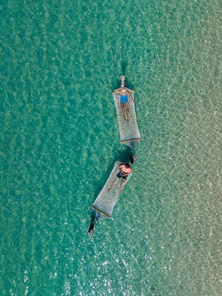 Entspannen in Hängematten über dem kristallklaren Wasser der Insel Koh Kood, Thailand A couple peacefully lounge in colorful hammocks suspended over turquoise waters. Gentle ripples reflect sunlight, creating a serene atmosphere on Koh Kood Island, a tropical paradise in Thailand (License=RF) ,model released, Symbolfoto Copyright: xZoonar.com FokkexBaarssenx 24389221 ,model released, Symbolfoto ,property released