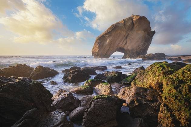 Penedo do Guincho steht majestätisch am Praia da Santa Cruz, als die Meereswellen bei Sonnenuntergang gegen den Sandstrand prallen Penedo do Guincho stands majestically at Praia da Santa Cruz as ocean waves crash against the sandy beach during sunset Copyright: imageBROKER DmitryxRukhlenko ibxdmr15961464.jpg