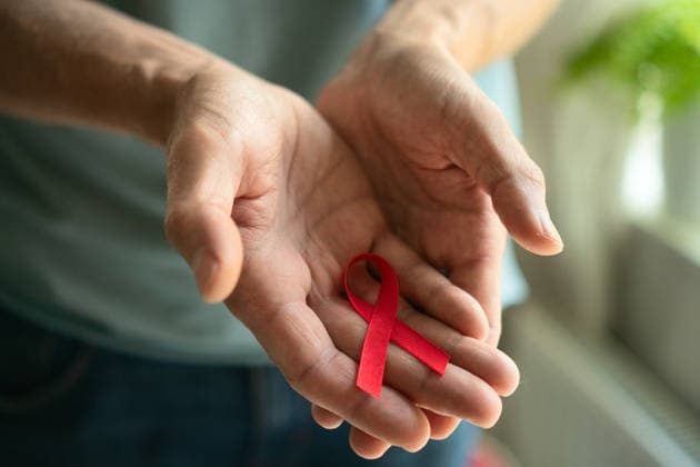 Mann präsentiert rote Schleife zum Welt-AIDS-Tag Close-up of male hands offering red awareness ribbon on palm, representing December HIV AIDS remembrance, support, and medical solidarity. (License=RF) ,model released, Symbolfoto Copyright: xZoonar.com elenaxskorobogatovax 24385696 ,model released, Symbolfoto ,property released