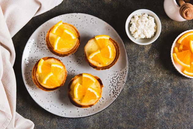 Mini gebackene Teer mit Hüttenkäse und Orange auf einer Platte auf der Tischplatte Mini baked tarts with cottage cheese and orange on a plate on the table top view (License=RF) Copyright: xZoonar.com ElenaxRuix 24399194
