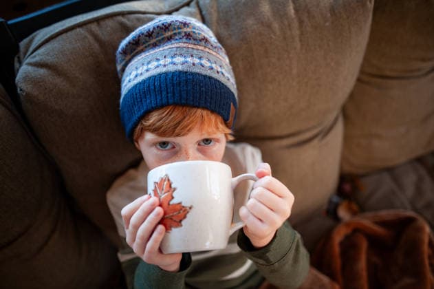 Candid childhood moment redheaded boy holding mug on couch Grimes, Iowa, United States CR_LIPF251218-1916538-01 ,model released, Symbolfoto