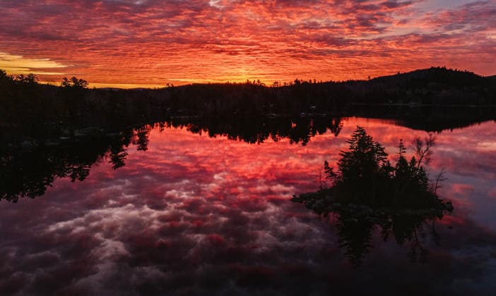 Sunrise reflected in peaceful lake with island, Phillips Lake, Maine Dedham, Maine, United States CR_SSNF25121866-1907591-01