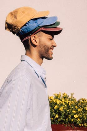 Side view of playful young man wearing multi colored caps against wall Sweden, Stockholm, model released Copyright: xMaskotx , MA122097 MA122097