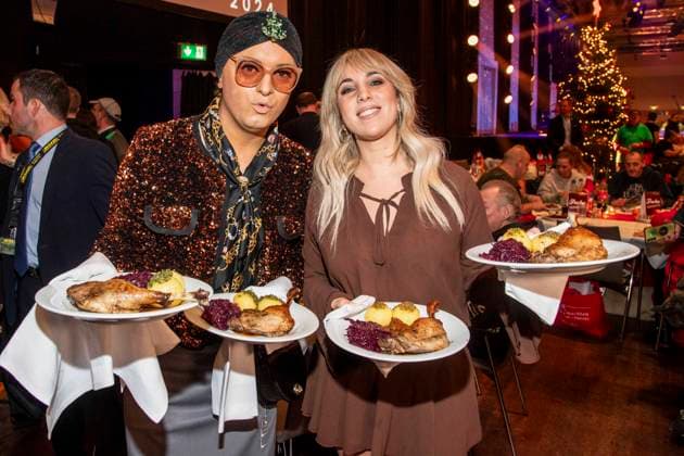 abb: Julian F. M. Stoeckel und Annemarie Eilfeld als Promi Kellner beim Servieren von Teller mit Gaensekeuele Rotkohl und Kloesse bei der 31. Frank Zander Weihnachtsfeier Weihnachtsessen fuer Obdachlose und Beduerftige Menschen 2025 im Estrel Convention Center am 22.12.2025 in Berlin Berlin Deutschland