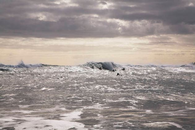 Surfer waiting for a big wave at Bethells Beach under cloudy sky, GWF001263