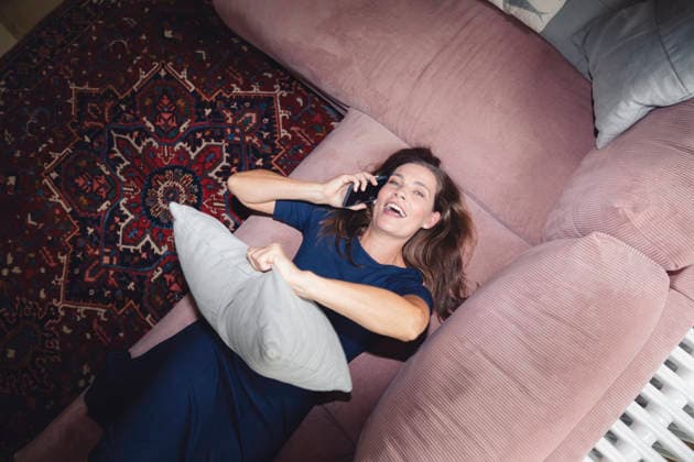 Playful woman lying on sofa and talking through smart phone at home model released, Symbolfoto property released, KNSF10581