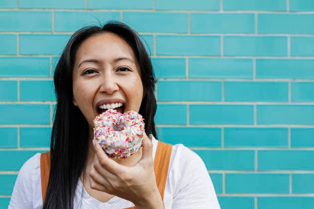Woman enjoying donut with sprinkles against turquoise wall model released, Symbolfoto, ASGF06702