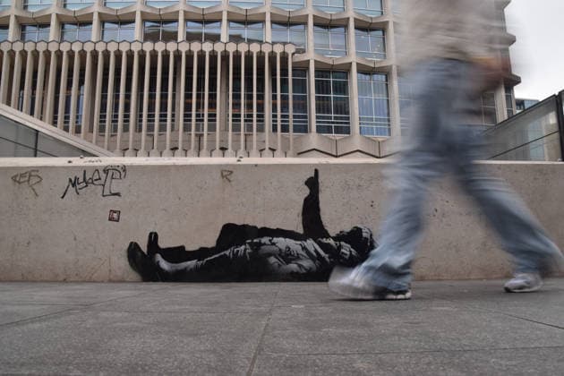 December 23, 2025, London, United Kingdom: A person walks past the new Banksy artwork on a wall outside Centre Point and Tottenham Court Road station. Two identical new artworks, one of which has now been confirmed by elusive street artist Banksy, have appeared outside Centre Point and on an unoccupied mews building in Bayswater. The artworks depict two children lying on their backs and one child pointing upwards. London United Kingdom - ZUMAs197 20251223_aab_s197_032 Copyright: xVukxValcicx