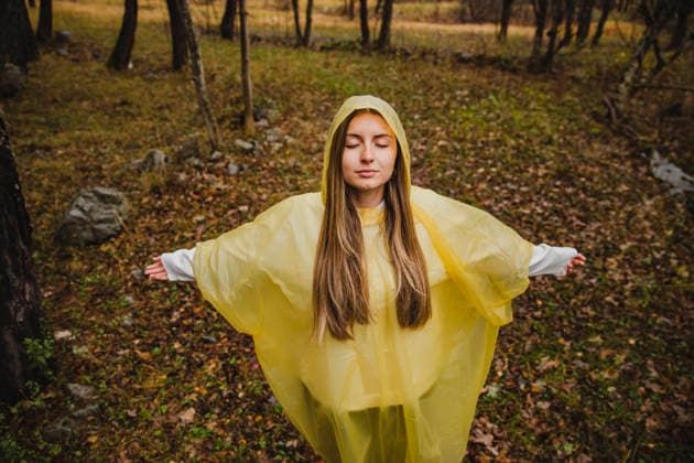 Woman in yellow raincoat standing with arms open in autumn forest model released, Symbolfoto, ACPF01664