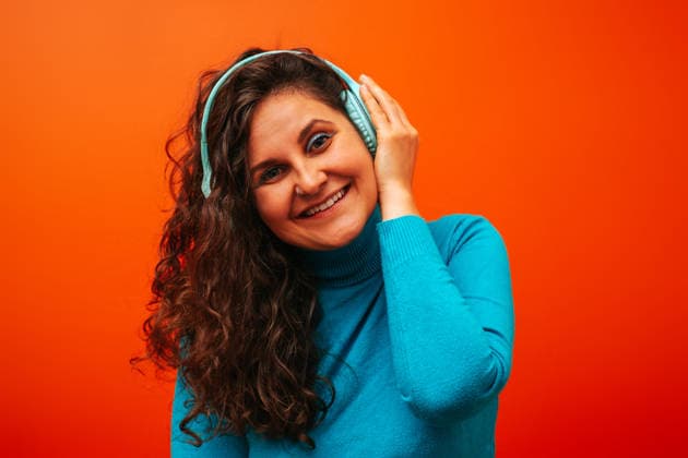 Woman with curly hair listening to music and smiling in blue turtleneck model released, Symbolfoto, AAF00345