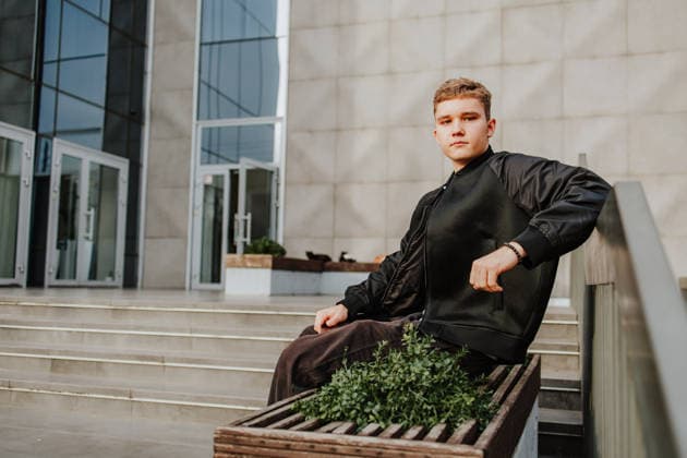 Student sitting seriously on a bench in a modern school yard model released, Symbolfoto property released, MDOF03184