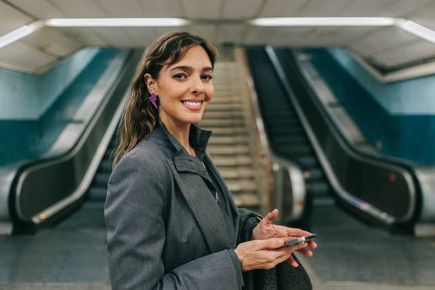 Businesswoman smiling in Madrid metro station holding phone commute model released, Symbolfoto, FOMF00653
