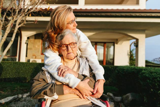 Mature woman hugging senior woman in wheelchair outdoors showing care model released, Symbolfoto, SIF01516